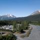 Clear aerial/drone view showing the full campground layout with RV pitches, access road/riverbed, surrounding trees and mountains — excellent overview for a property gallery (image sourced from the site's Features page).