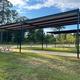 Photo of covered pull-through pads with picnic tables and paved pads beneath metal canopies — highlights site features and shaded RV parking. Source page context shows this as an on-property amenity.