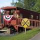 Clear photo of the distinctive red caboose building used as on‑site feature/office, with ramp and railroad crossing sign — good property-identifying image from the homepage.