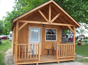 Small standalone cabin with porch on gravel pad and RVs visible in background — depicts cabin lodging available on the property (from site camping/gallery pages).