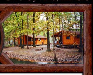 Cabin cluster among trees at the water’s edge — matches cabin rentals and lakeside setting described on the homepage and cabin rental pages (visual evidence of on-site cabins by a pond).