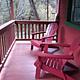Front porch and two red Adirondack of red cabin.