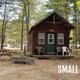 Exterior view of a small rustic cabin on-site with surrounding trees and nearby campsites; matches the Cabin Rental page context.