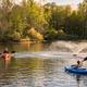 Kayakers on the on-site lake, showing water activities and shoreline scenery — clearly depicts recreational features of the campground and is hosted on the site.