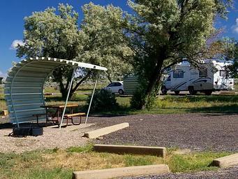 Campsite with a picnic table and fire pit. Forest users are at other campsites in the background.