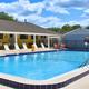 Clear blue heated outdoor swimming pool surrounded by lounge chairs at Blue Parrot RV Resort deck.
