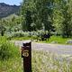 Campsite sign #12, gravel road, mountains and trees.