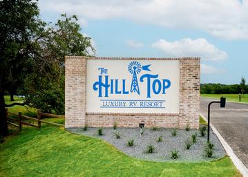 Entrance monument sign for The Hill Top at Brenham set at the property entrance — confirms property identity and arrival experience (homepage/gallery).