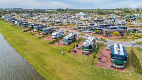 High-angle photo of lined RV sites along the lakeshore showing individual pads, hookups and landscaping — useful for showcasing RV accommodations (site home page image).
