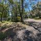 Gravel campsite/RV pad among oak trees with utility hookups visible — illustrates typical site layout and shady tree cover (from amenities page).