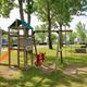 Playground with visible RV sites and trees in the background — useful for showing family amenities and site layout (source page: homepage images).