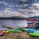 Beach scene with stacked kayaks, dock and shoreline — shows on-site water recreation and equipment storage, supporting campground amenities shown on the Map page.