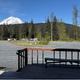 View from a deck overlooking gravel RV sites and picnic tables with a prominent mountain in the distance — highlights campsite foreground and scenery (homepage source).