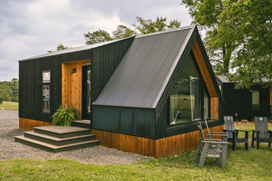 Modern black-clad cabin with A-frame window and outdoor seating on gravel — demonstrates another style of on‑property lodging and grounds context from the resort gallery.