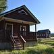 Paddy Flat Guard Station East - front of rustic cabin showing porch and stairs with blue skies and mountains beyond