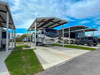 Covered RV parking row showing metal awnings and concrete pads — useful detail of covered site options advertised on the site.