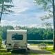 Rear view of an RV parked at a lakeside campsite with picnic table and fire ring — shows a typical RV pitch on the campground with direct lake access; comes from the site’s attractions/gallery.