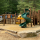 Outdoor playground structure (slides, climbing elements) on wood-chip surface — clear image of on-site family amenities referenced on the property website.
