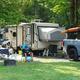 RV site with trailer, truck and campsite setup — clearly shows typical RV pitches and site layout (labeled 'RV Camping' on site background image).