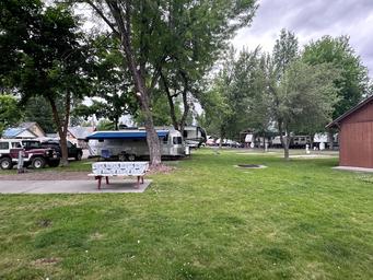 Wide view of green lawn, picnic table and multiple RVs in the background — good general overview of campground grounds and guest spacing; used as a background image on the property page.