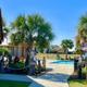 Color photo showing pool area with tiki/palapa shade structures and landscaping — from the site's 'Amenities' page and useful to display on-site facilities.