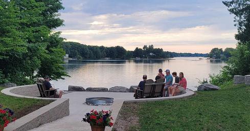 Waterfront communal fire-ring seating overlooking the lake with guests — highlights shared amenities and the scenic shoreline setting (source page: /amenities/).