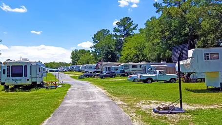 Ground-level view down a paved interior road with RVs and trailers on both sides — good depiction of typical RV pitches and internal roads. (sourced from the property site).