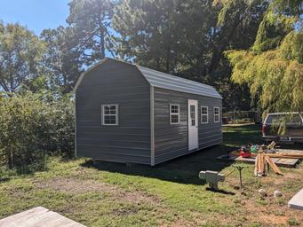 Exterior view of a standalone cabin on grass near trees — shows the property’s cabin accommodation option.
