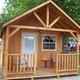 Small standalone cabin with porch on gravel pad and RVs visible in background — depicts cabin lodging available on the property (from site camping/gallery pages).