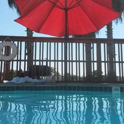 Pool-level view showing the swimming pool, umbrella and decking — illustrates onsite leisure amenity guests can use.