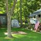 Shows RV sites with level grassy pads, trees, and site details (awnings, decor) — useful to illustrate campsite layout; image is a slide on the campground site.