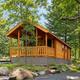 Raised family cabin set among landscaping and trees, highlighting cabin style and site features — matches cabin inventory on the campground site.