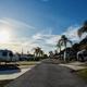 Clear wide photo down an RV park roadway showing multiple paved pads, Airstreams, palm trees and site layout — matches the property ‘View Our Sites’ page (accommodation) and depicts campground pitches.