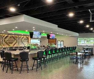 Interior shot of the Bar & Grill (bar seating and tables) — matches page context stating the on‑site restaurant and shows a facility guests can use.