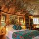 Interior bedroom (Biblioteque) with bed, built-in bookshelves and decorative lighting — showcases interior character and guest accommodations from the treehouses page.