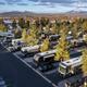 Elevated/drone view of multiple RVs parked in designated paved sites with trees and mountains in background — identifies typical RV pitch arrangement (DJI_0196-copy).
