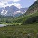 The purple Maroon Bells peaks over Maroon Lake with wildflowers in the foreground
