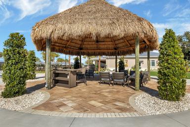 Photo of a thatched-roof palapa seating area near the clubhouse and pool—shows outdoor shaded gathering space featured in the property gallery.