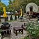 Covered-wagon style lodging and a furnished patio with chairs and umbrellas — shows a unique on-site lodging option and landscaped guest area from the campground’s imagery.