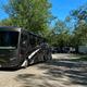 Wide view of a motorhome with multiple RVs in background on a spacious gravel pad — useful overview of RV parking and site spacing from the park photos gallery.