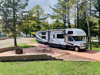 Concrete patio full-hookup RV site with picnic table and fire ring — useful for showing premium RV pitch layout and onsite hardscape as seen on the park’s sites descriptions.