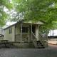 Cabin on-site with picnic table, gravel pad and nearby RVs — clearly shows cabin accommodation and campsite layout (labeled Cabin Rentals on site pages).