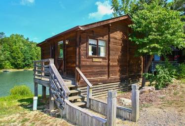 Close-up of a lakeside wooden cabin on stilts — highlights cabin accommodation style available at the resort.