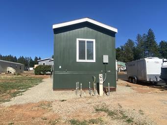 Rear/exterior view of a mobile home with adjacent RV — demonstrates mixed mobile-home and RV presence on-site (used in Lot 52 listing context).