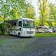 Clear photo of full-hookup RV sites and pull-through parking with trees and gravel pads — useful to show RV accommodations and site setup.