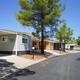 Street-level view of manufactured homes and covered carports with mountains in background — good representation of home sites and community streets (from the homes-for-sale section).