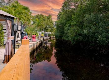 View along a landscaped canal/boardwalk with residential patios visible — shows on-site waterfront/canal setting and appears in the property’s gallery imagery.