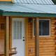 Close view of a lakeside log cabin on the property (porch, wood exterior). Context label on the rates page references rentals/cabins, confirming this is an on-site accommodation.