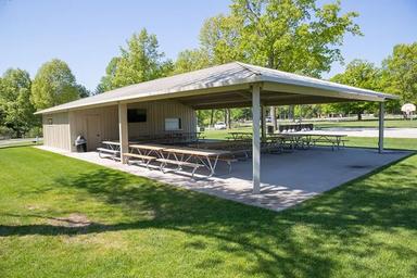 Large covered pavilion with picnic tables on grassy area — demonstrates a key amenity and gathering space listed on the amenities page.