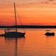 Silhouette of sailboat and small boat at sunset on the water—represents boating activity and waterfront character of the marina property.